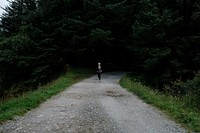 Woman jogging down an empty forest road