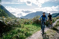 Couple cycling down a road in the Scottish Highlands