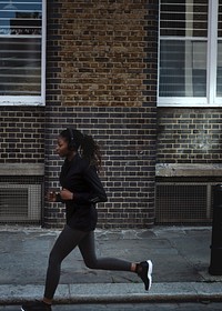 Woman listening to music while jogging in a city