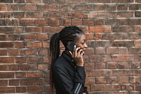 Woman on the phone by a brick wall