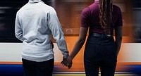 Couple holding hands as the train goes by