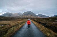 Woman walking on a road in Glen Etive, Scotland