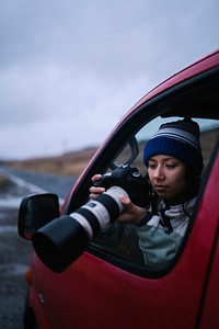 Woman taking a photo out of the car window
