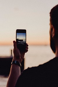 Man capturing a picture of the lake at dusk