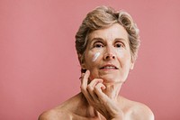 Elderly woman applying facial cream