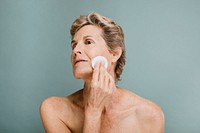 Elderly woman wiping her face with a cotton pad