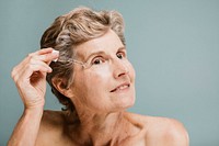 Senior woman applying moisturizer on her eye wrinkles