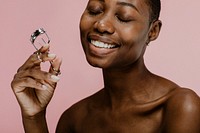 Cheerful black female beauty blogger using an eyelash curler