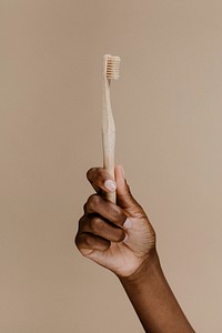 Black hand holding a wooden toothbrush