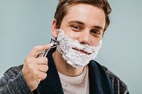 Young man shaving his beard