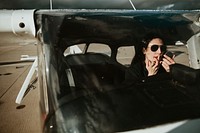 Airwoman applying red lipstick in the cockpit