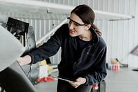 Female aviation technician repairing the motor of a propeller plane