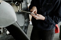 Female aviation technician repairing the motor of a propeller plane