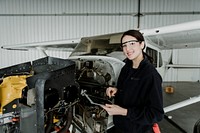 Female aviation technician repairing the motor of a propeller plane