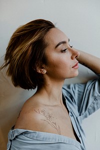 Portrait of a short hair woman with an expedition tattoo on her shoulder side view