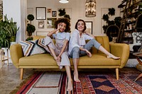 Portrait of a cheerful lesbian couple at a yellow couch