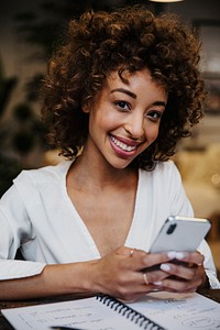 Cheerful black woman using her phone in a house