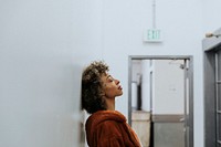 Woman in a brown coat leaning against a wall