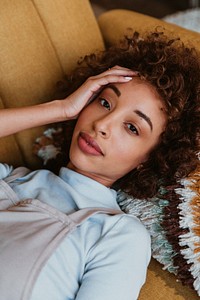 Closeup of a woman lying on a mustard yellow couch