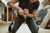 Female carpenter drilling a lumber