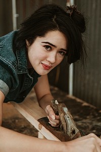 Female carpenter shaping lumber with a hand plane