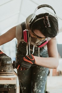 Female carpenter smoothing the lumber with a sander