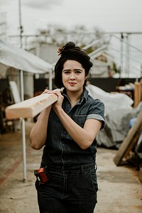 Female carpenter carrying a lumber on her shoulder