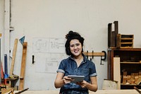 Cheerful female carpenter using a tablet in her workshop