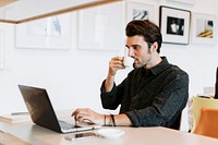 Man sipping a coffee while working
