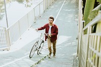 Caucasian man pushing his bicycle up the hill