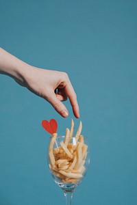Woman picking french fries from a wine glass