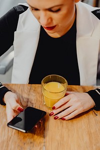 Woman having a glass of juice and checking her phone