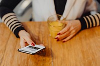 Woman having a glass of juice and checking her phone