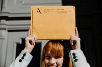 Woman holding a brown envelope mockup above her head