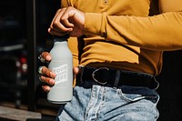 Man in a yellow long sleeve top opening a gray stainless steel tumbler bottle mockup