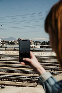 Woman capturing a view at a platform by her phone