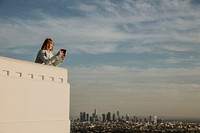 Woman capturing the Los Angeles view with her phone at the Griffith Observatory, USA