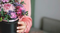 Woman in pink holding a pot with fresh flowers