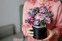 Woman in pink holding a pot with fresh flowers