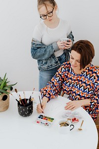 Female artist painting while her daughter is watching