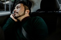 Man in a car with wireless earphones looking out the window