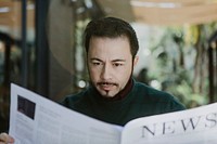 Man reading a newspaper in a cafe