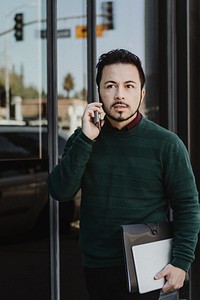 Man talking on the phone carrying a digital tablet and a notebook