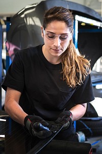 Female mechanic pulling out the weather seal of a vehicle