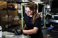 Female mechanic drilling into metal