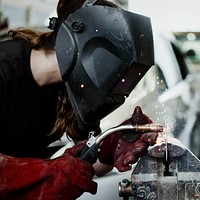 Female welding a metal piece in the garage