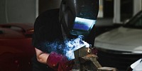 Female welding a metal piece in the garage