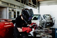 Female welding a metal piece in the garage