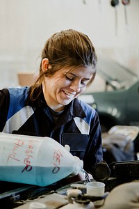 Female mechanic pouring water into the radiator
