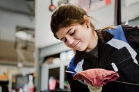 Young female mechanic wiping the engine oil dipstick